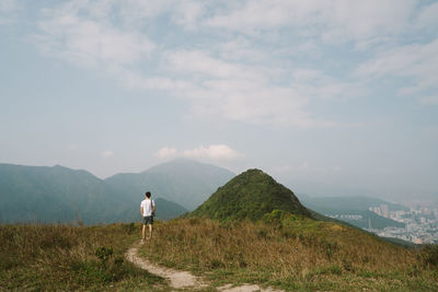 Rear view of man walking on mountain against sky