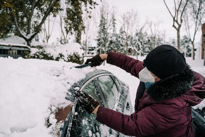 Rear view of person holding umbrella during winter