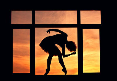 Silhouette woman standing on window