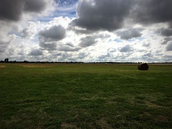 Scenic view of grassy field against cloudy sky