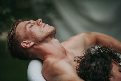 Portrait of shirtless man with arms raised