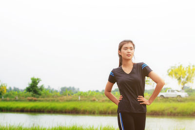 Young woman standing on field against clear sky