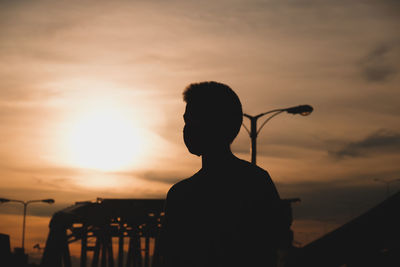 Rear view of silhouette man standing against sky during sunset