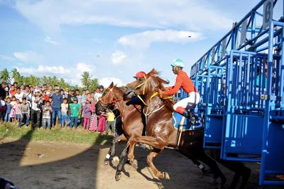 Group of people riding horse cart against sky