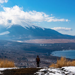 Rear view of person looking at snowcapped mountain mt. fuji against sky
