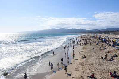 People at beach against sky on sunny day