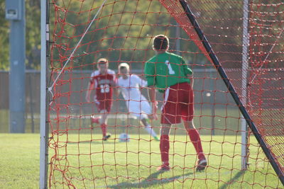 Teenagers playing soccer on field