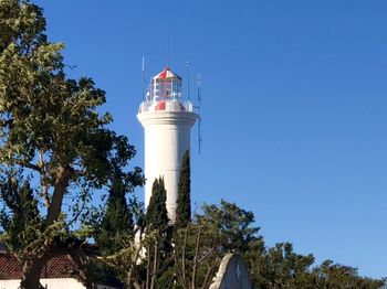 Low angle view of lighthouse by building against clear blue sky