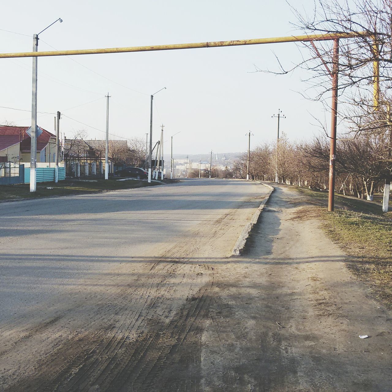 clear sky, transportation, road, built structure, the way forward, building exterior, architecture, street, empty, copy space, sky, day, outdoors, tree, no people, sunlight, diminishing perspective, asphalt, street light, house