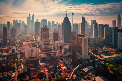 Aerial view of buildings in city against cloudy sky