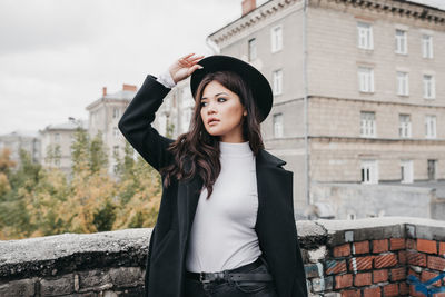 Portrait of beautiful woman standing against building in city