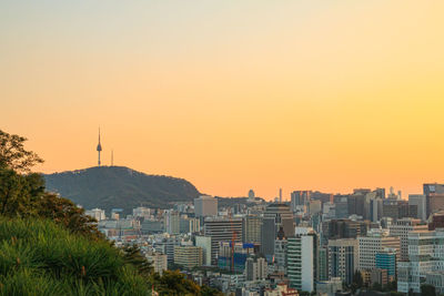 Buildings in city against clear sky during sunset