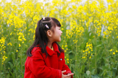 Cute girl standing against yellow flowering plants