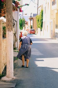 Rear view of woman walking by building in city