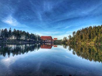 Reflection of trees and buildings in lake against sky