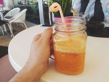  hand holding orange juice in glass on table