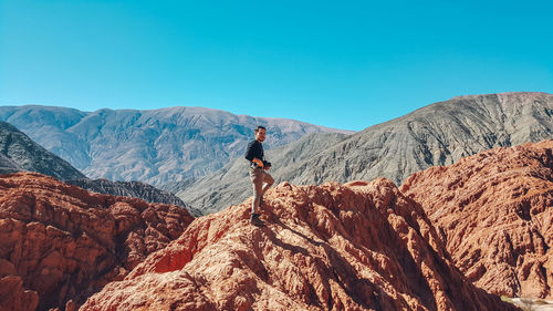 Rear view of person on rocks against sky