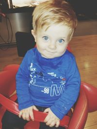 Close-up portrait of boy sitting against blue wall