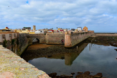 Bridge over canal against cloudy sky