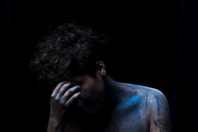 Close-up of man covered with powder paint against black background