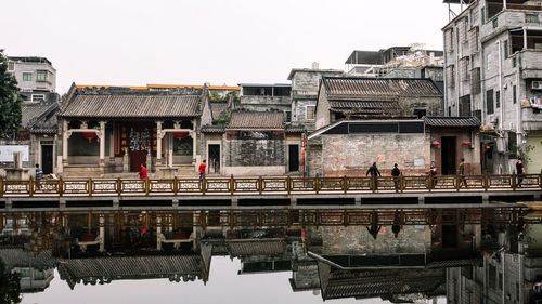 People on bridge over lake by houses in village