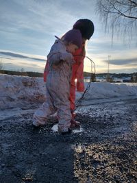 Girl standing in snow against sky during winter