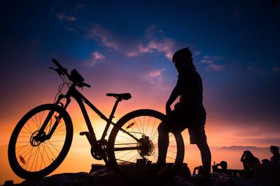 Silhouette man with bicycle against sky during sunset