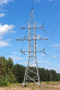 Low angle view of electricity pylon on field against sky