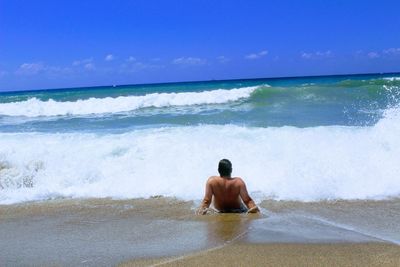 Rear view of shirtless man in sea against clear sky