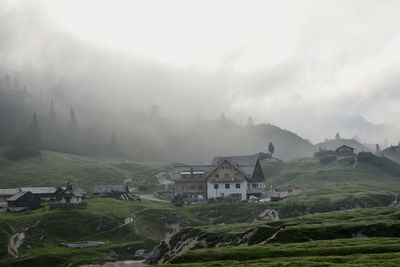 Houses on field by buildings against sky