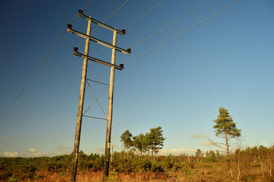Low angle view of electricity pylon on field against sky. 