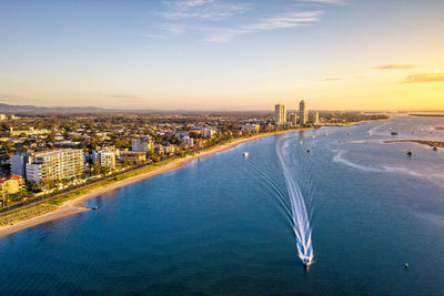 High angle view of sea and buildings against sky at sunset