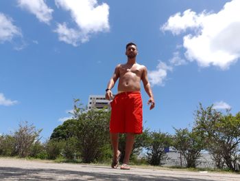 Full length of shirtless man standing against sky