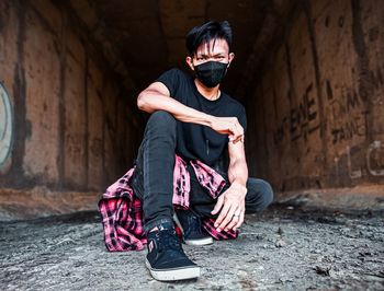 Young man sitting on wall