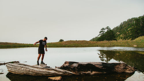 Full length of man standing by lake against clear sky