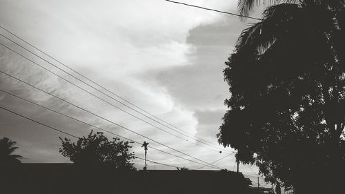 Low angle view of electricity pylon against cloudy sky