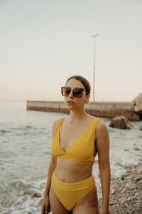 Young woman wearing sunglasses while standing at beach