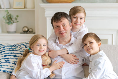 Portrait happy family dad with little children sit relax on couch hugging