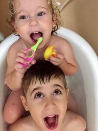 Cute siblings sitting in bathtub at home