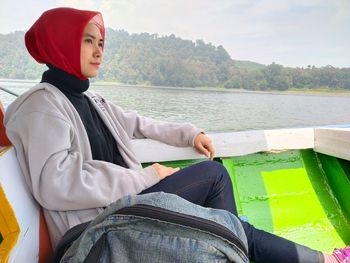 Side view of woman sitting on boat in lake