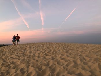 People on beach against sky during sunset