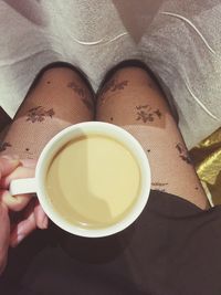 Cropped image of hand holding coffee cup while sitting