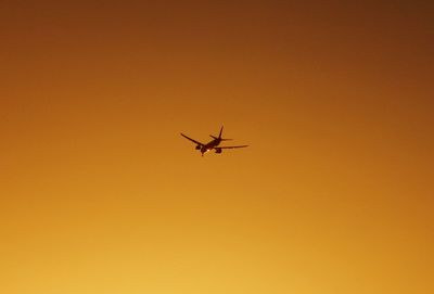 Low angle view of silhouette airplane flying against clear sky