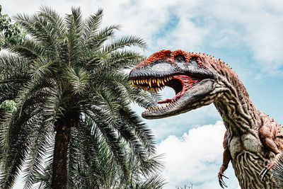 Low angle view of dinosaur statue against sky