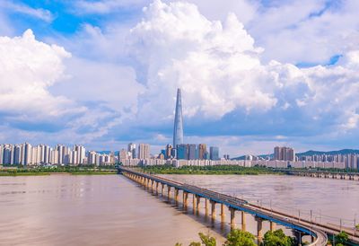 View of river and buildings against cloudy sky