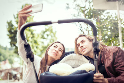 Portrait of young woman photographing with mobile phone