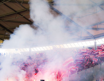 People enjoying amidst smoke at stadium