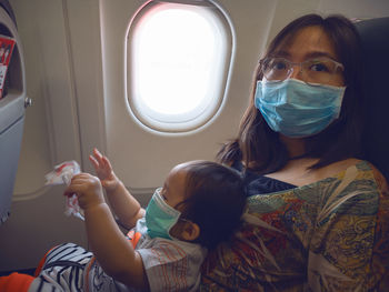 Portrait of a young woman looking through window