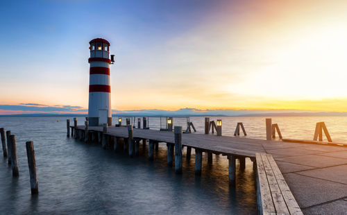 Pier over sea against sky during sunset