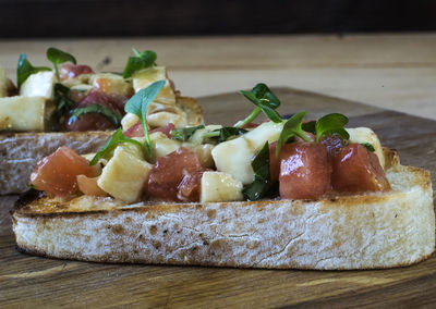 Close-up of bruschetta served with tomatoes on cutting board